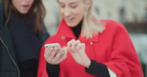 Two young girls using mobile phone in a city. Видео 104623713