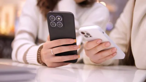 Two young girls using mobile phones while sitting at the cafe indoors mall. Two Stock Footage 267256824