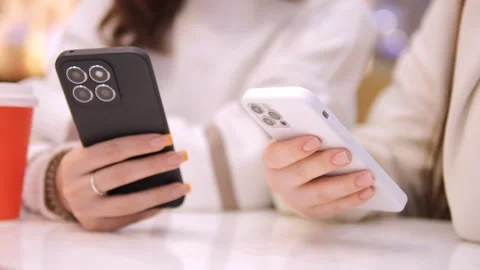 Two young girls using mobile phones while sitting at the cafe indoors mall. Two Stock Footage 270396962