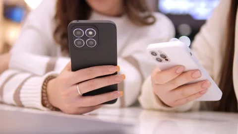 Two young girls using mobile phones while sitting at the cafe indoors mall. Two Stock Footage 271316861