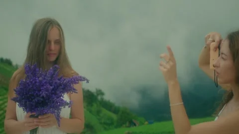 Two young girls in white dresses are photographed on top of a mountain Stock Footage 280970010