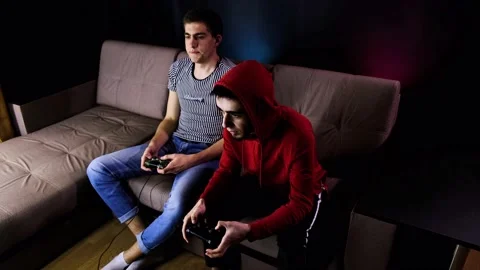 Two young guys are sitting on the couch in front of the TV and playing a game Stock Footage 134205139