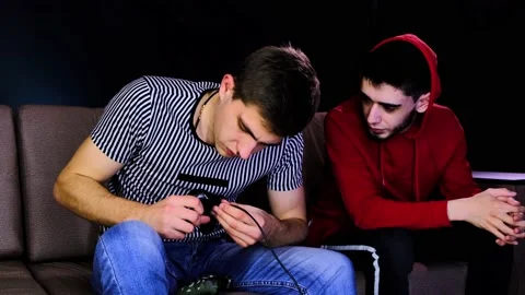 Two young guys are sitting on the couch in front of the TV and setting cable Stock Footage 134205318