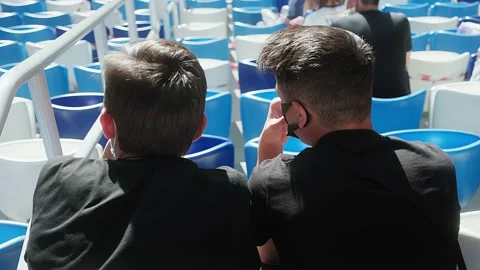 Two young guys are sitting in the stadium and discussing a football match Stock Footage 139888518
