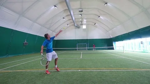 Two young guys playing tennis on court in slowmotion Stock Footage