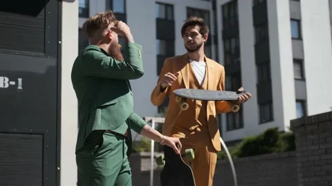 Two young guys in suit walking city with skateboard,laughing smiling,high five Stock Footage 147473720