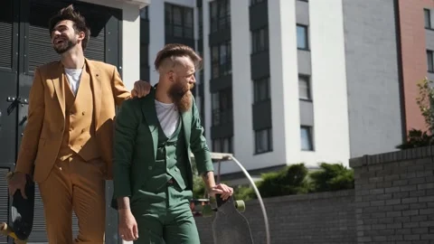 Two young guys in suit walking city with skateboard,laughing smiling, concept of Stock Footage 147473813