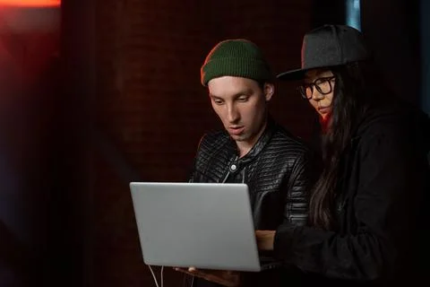 Two young hackers with laptop decoding information Stock Photos