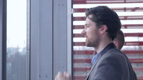 Two young handsome businessmen looking through the window at the city. Stock Footage 82232640