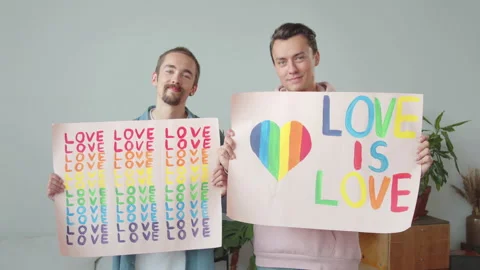 Two young handsome guys let up lgbt posters, look at each other and smile Stock Footage 174457310