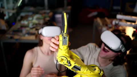 Two young happy engineers with VR virtual reality headsets fixing an yellow Stock Footage 247420328