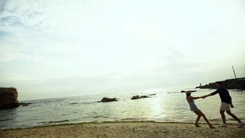 Two young happy people holding hands and having fun on the beautiful sand beach Stock Footage 70368395