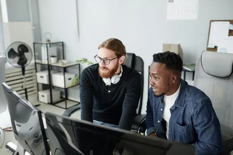 Two young intercultural diversity programmers looking at compute screen Stock-Fotos