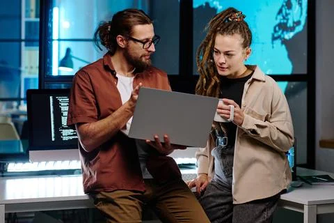 Two young IT engineers discussing online data on laptop screen Stock Photos