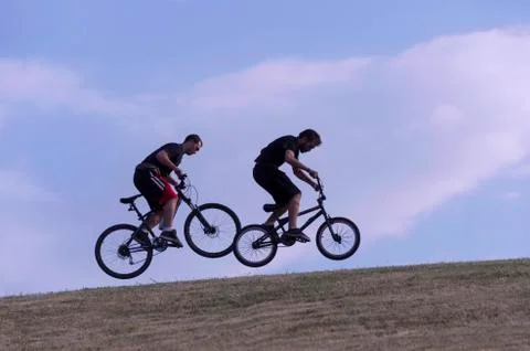 Two young, jumping with a bicycle Stock Photos