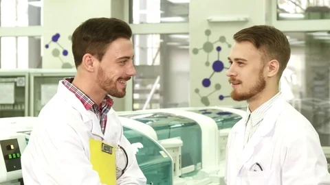 Two young lab technicians stand in the middle of the laboratory and talk Stock Footage 84866058