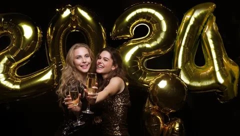 Two young ladies drinking champagne. Image of girls with balloons isolated .. Stock Photos