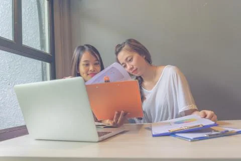 Two young ladies working on documents next to computer Foto stock