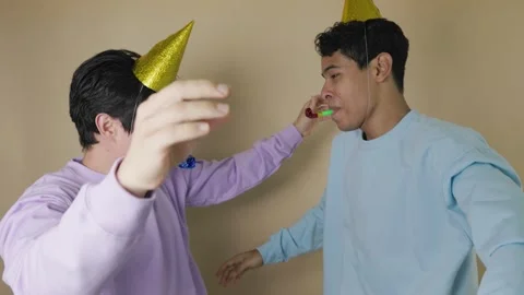 Two young Latinos jumping with joy wearing golden party hats and party blow.. Stock Footage 317250977