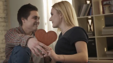 Two young lesbians cute look at each other, holding a heart sign in their hand Stock Footage 84943085