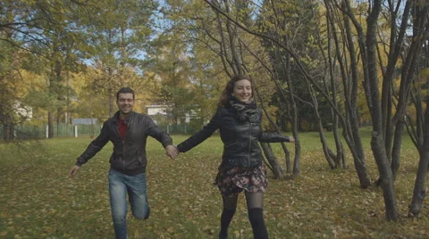 Two young lovers running across the meadow in the park Stock Footage 55798486
