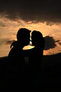 Two young lovers standing on sunset background Stock Photos