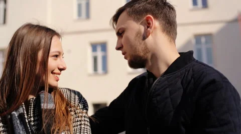 Two young lovers talking to each others while sitting on a bench at the street Stock Footage 61829586