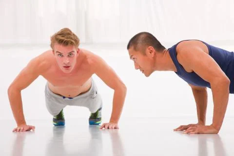 Two young male doing push-ups in gym Stock Photos