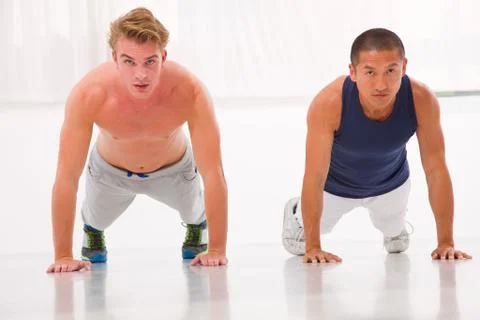 Two young man doing push-ups in gym Stock Photos
