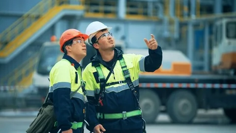 Two young man engineers disussing on oil factory Видео 76324756