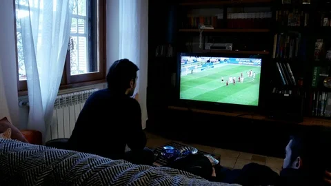 Two young man on a sofa, viewed from rear, watch a football match on a led tv Stock Footage 102232166