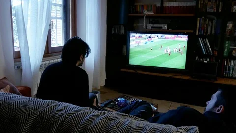 Two young man on a sofa, viewed from rear, watch a football match on a led tv Stock Footage 102232530
