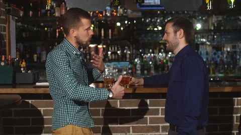 Two young man talking at counter. two friends standing in bar and drinking Stock Footage 70436164