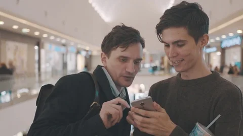 Two young man using smartphone in a shopping center. joyful guys watching video Stock Footage 70189000