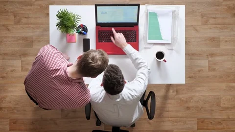 Two young mans talking over laptop and pointing in display, topshot, sitting Stock Footage 90551296