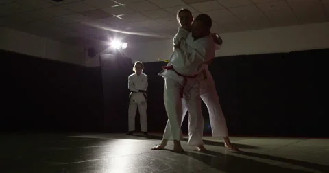 Two young martial arts athletes practice while a trainer assesses their moves. Stock Footage 48783011