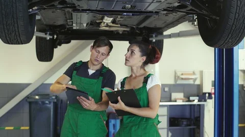 Two young mechanics of a guy and a girl are reading from the tablet a diagram Video stock 94655731