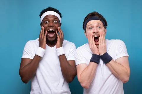 Two young men are ecscatic raising hands to their face. Stock Photos