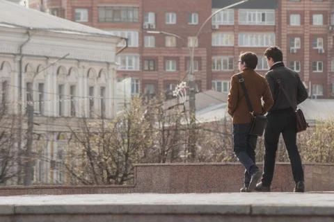 Two young men are returning from work, men are walking in the background of the Stock Photos