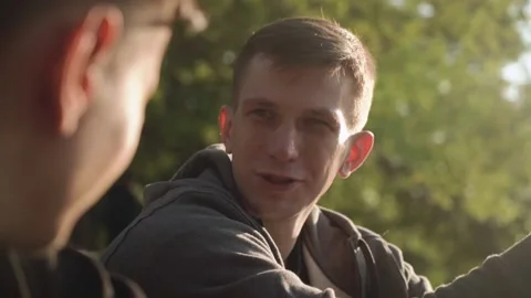 Two young men are talking in the city park. sunset. Slow motion. Stock Footage 208876501