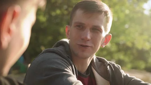 Two young men are talking in the city park. sunset. Slow motion. Stock Footage 208876582
