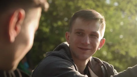 Two young men are talking in the city park. sunset. Slow motion. close-up Stock Footage 209304509