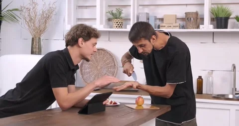Two young men are using a digital tablet and laptop in the kitchen Video stock 247472214
