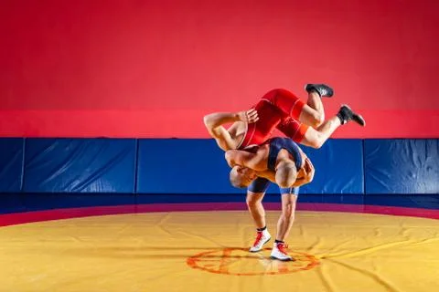 Two young men in blue and red wrestling tights are wrestlng and making a hip  Stock Photos