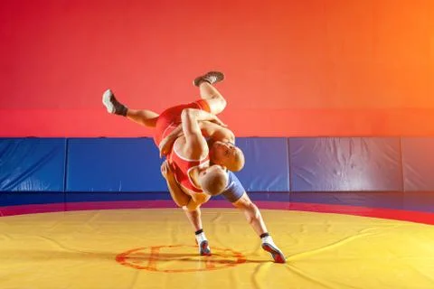 Two young men in blue and red wrestling tights are wrestlng and making a supl Stock Photos