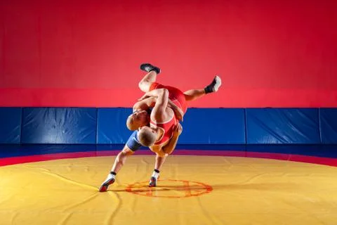 Two young men in blue and red wrestling tights are wrestlng and making a supl Stock Photos