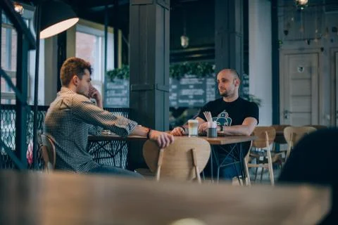 Two young men chatting in a cafe over a cup of coffee Stock Photos