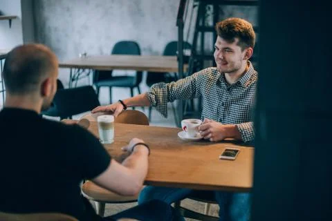 Two young men chatting in a cafe over a cup of coffee Stock Photos