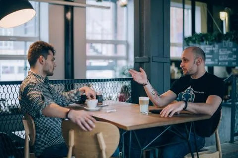 Two young men chatting in a cafe over a cup of coffee Stock Photos
