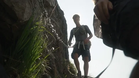 Two young men climbing down rocks while holding a chain, slow motion Stock Footage 129613990